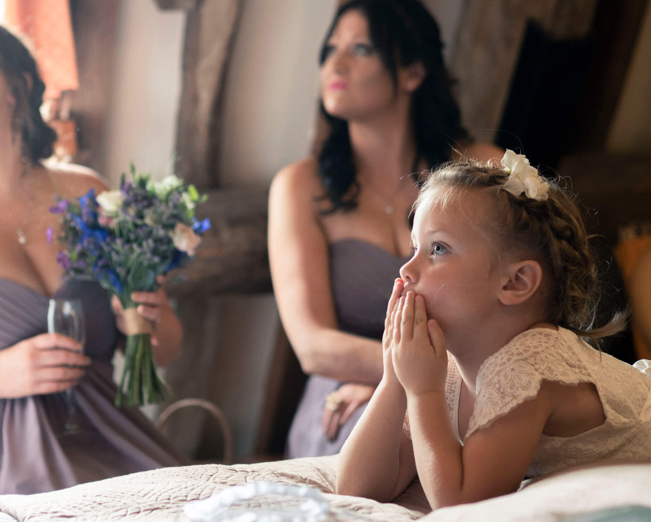 The bride's niece sits and watches her, spellbound.